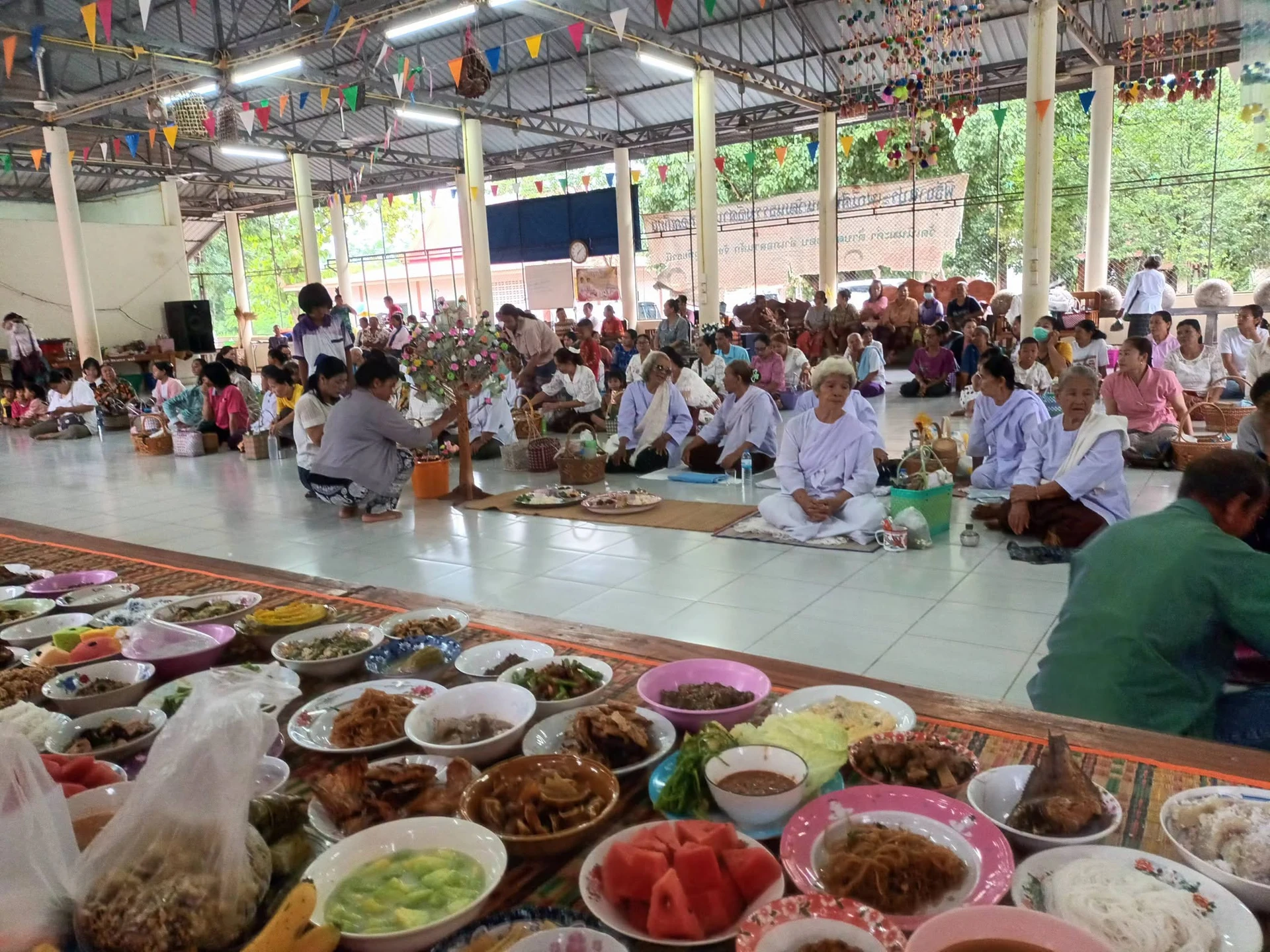 ผู้ร่วมทำบุญนั่งในศาลาพร้อมอาหารด้านหน้า จากโพสต์เตรียมงานวัดเนินมะค่า ไม่ใช่พิธีปลายเดือนธันวาคม