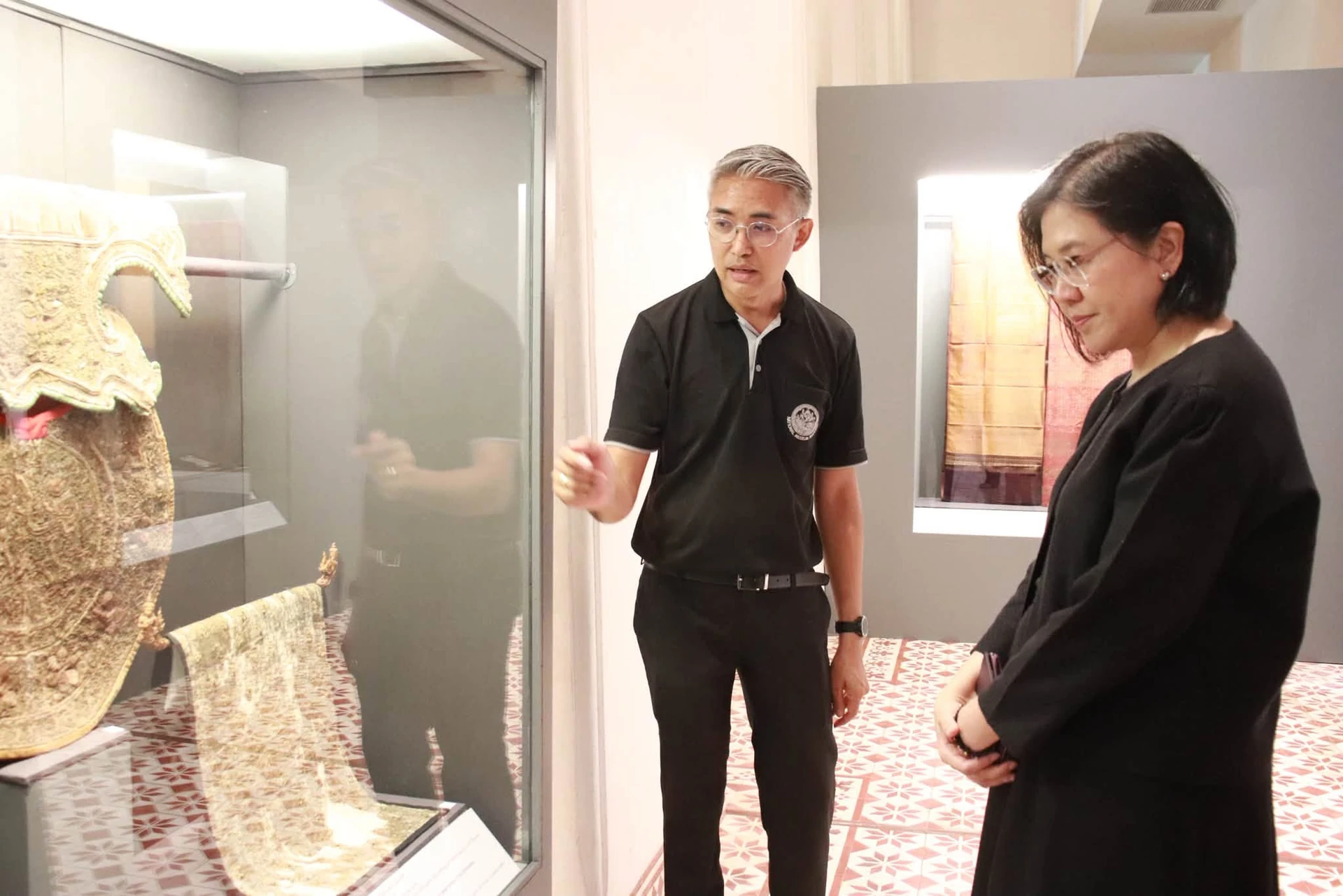 ผู้เข้าชมฟังคำอธิบายหน้าตู้จัดแสดงในนิทรรศการสยามพัสตราภรณ์พิไล จากรายงานพิพิธภัณฑ์วันที่ 17 กันยายน 2569