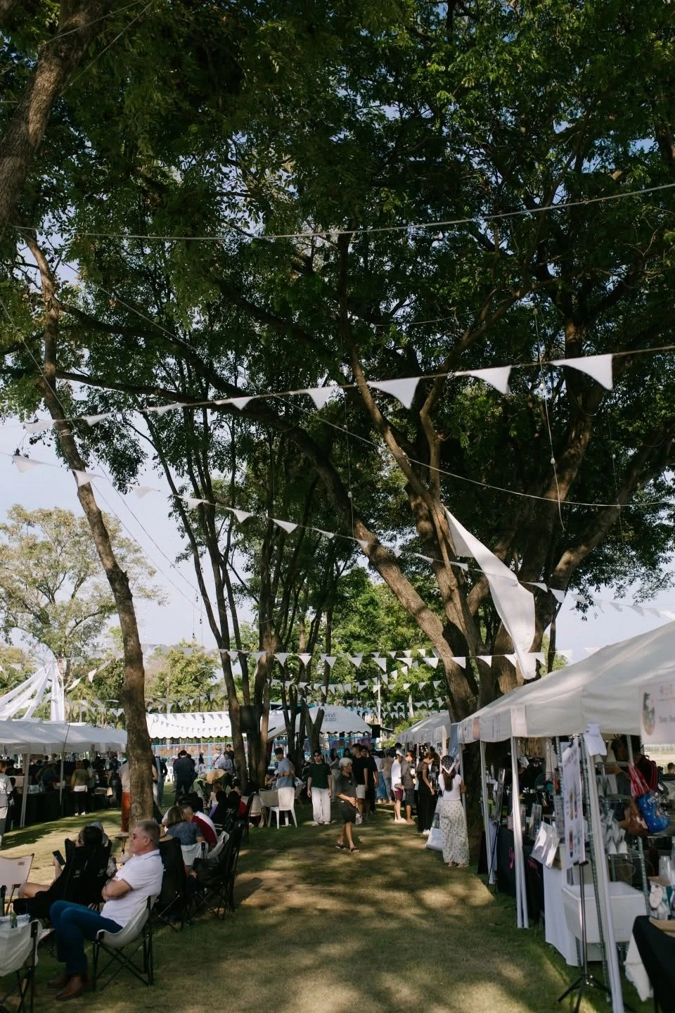 ผู้คนเดินและนั่งพักใต้ต้นไม้ระหว่างบูธ จากอัลบั้มบรรยากาศ Phichit Coffee Fest 2026